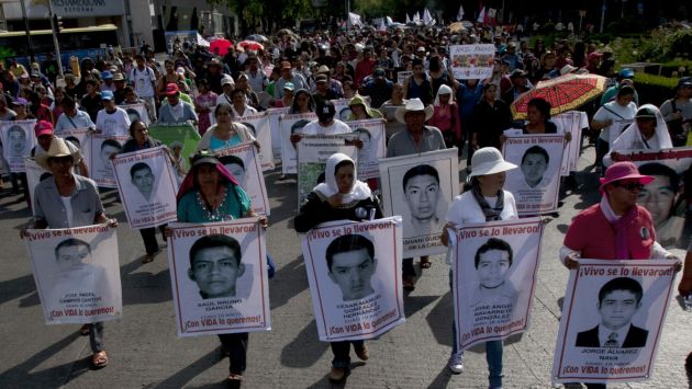 Relatives of the 43 missing students from the Isidro Burgos rural teachers college march holding pictures of their missing loved ones during a protest in Mexico City, Sunday, July 26, 2015.The search for 43 missing college students in the southern state of Guerrero has turned up at least 60 clandestine graves and 129 bodies over the last 10 months, Mexico's attorney general's office says. None of the remains has been connected to the youths who disappeared after a clash with police in the city of Iguala on Sept. 26, and authorities do not believe any will be.  (AP Photo/Marco Ugarte)